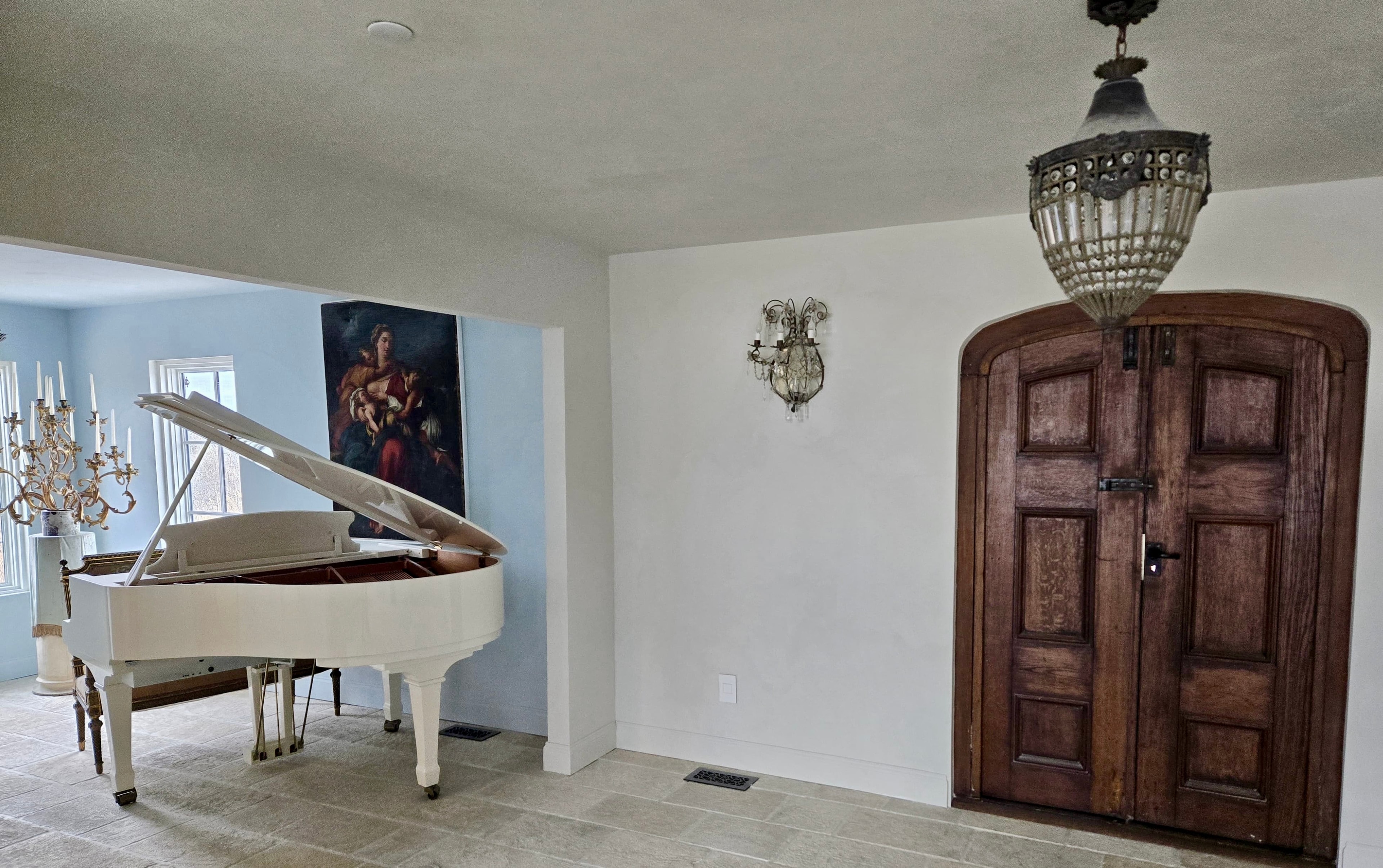 Grand family room renovation with white grand piano, arched door and crystal chandelier