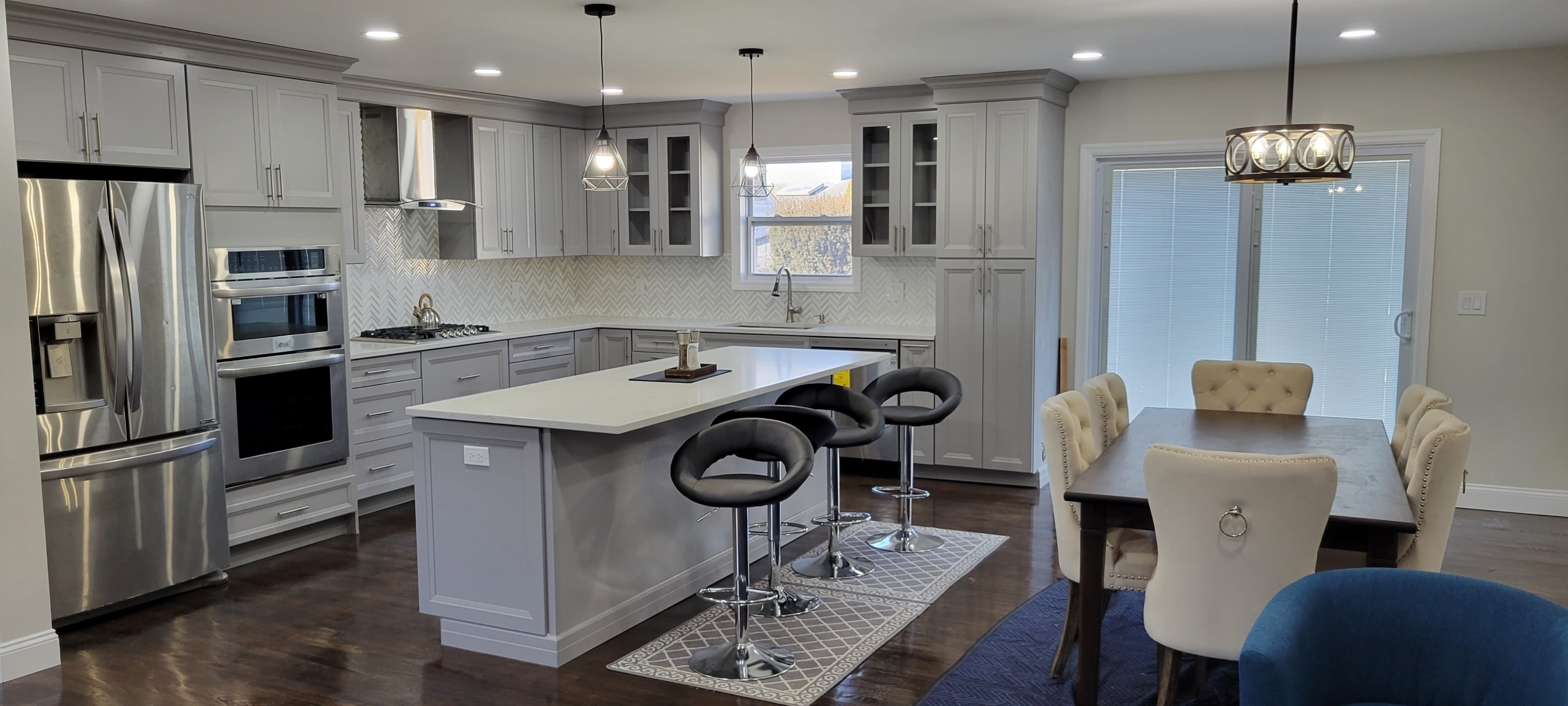 Kitchen remodel with gray shaker cabinetry, island bar stools and dining area