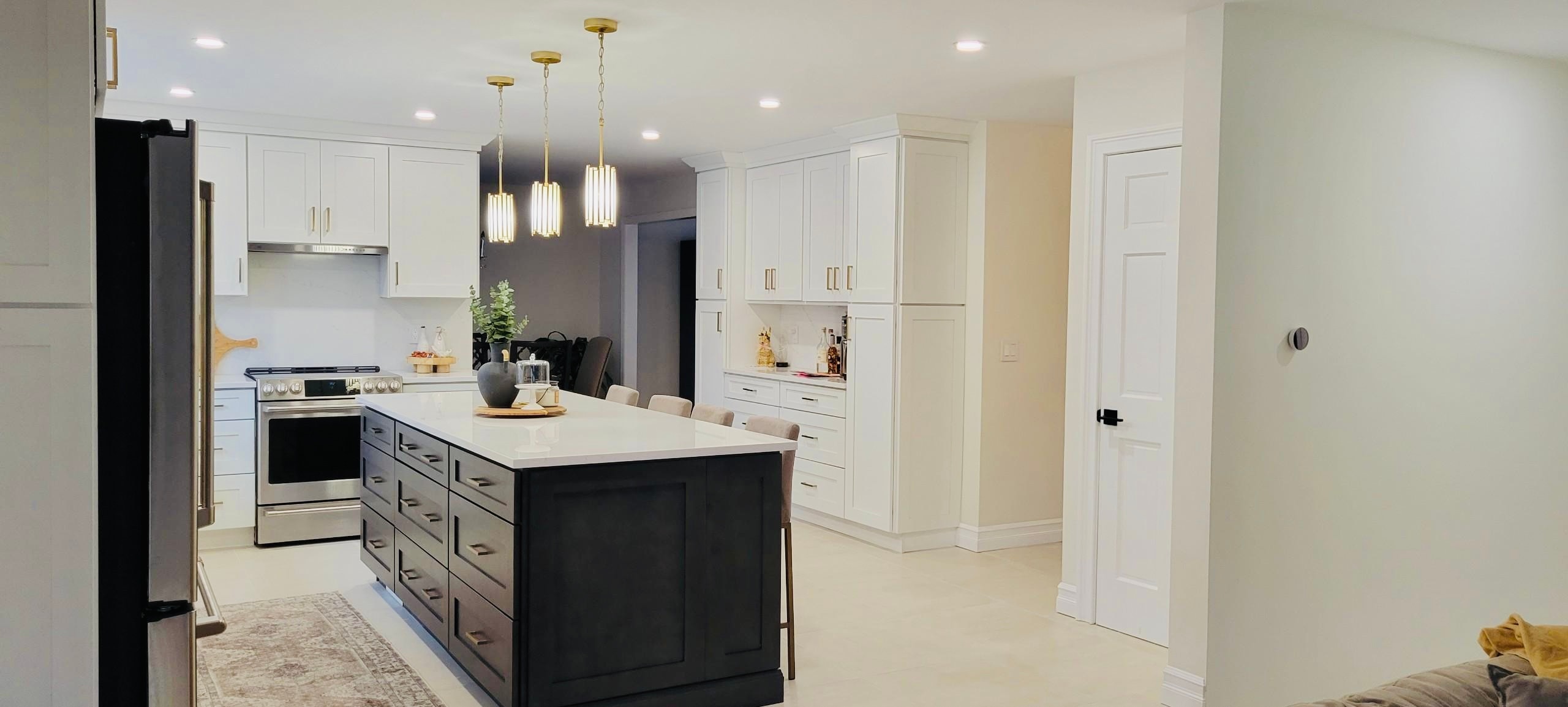 Kitchen remodel with white cabinetry, black island and gold pendant lights