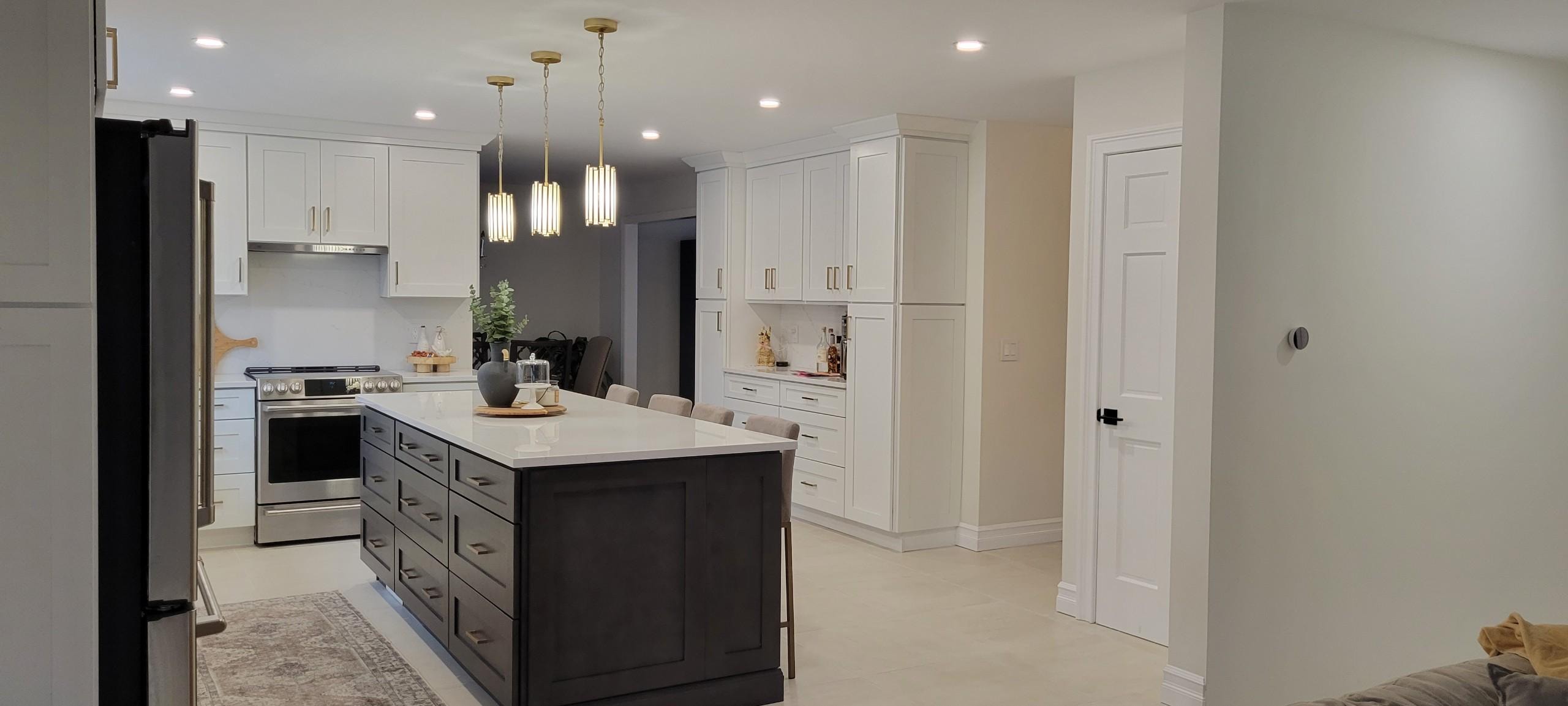 Kitchen remodel with white cabinetry, dark island and gold pendant lights